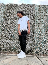 a man in a white t - shirt leaning against a wall